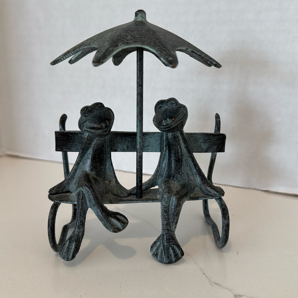 Vintage brass frogs on bench under a
umbrella